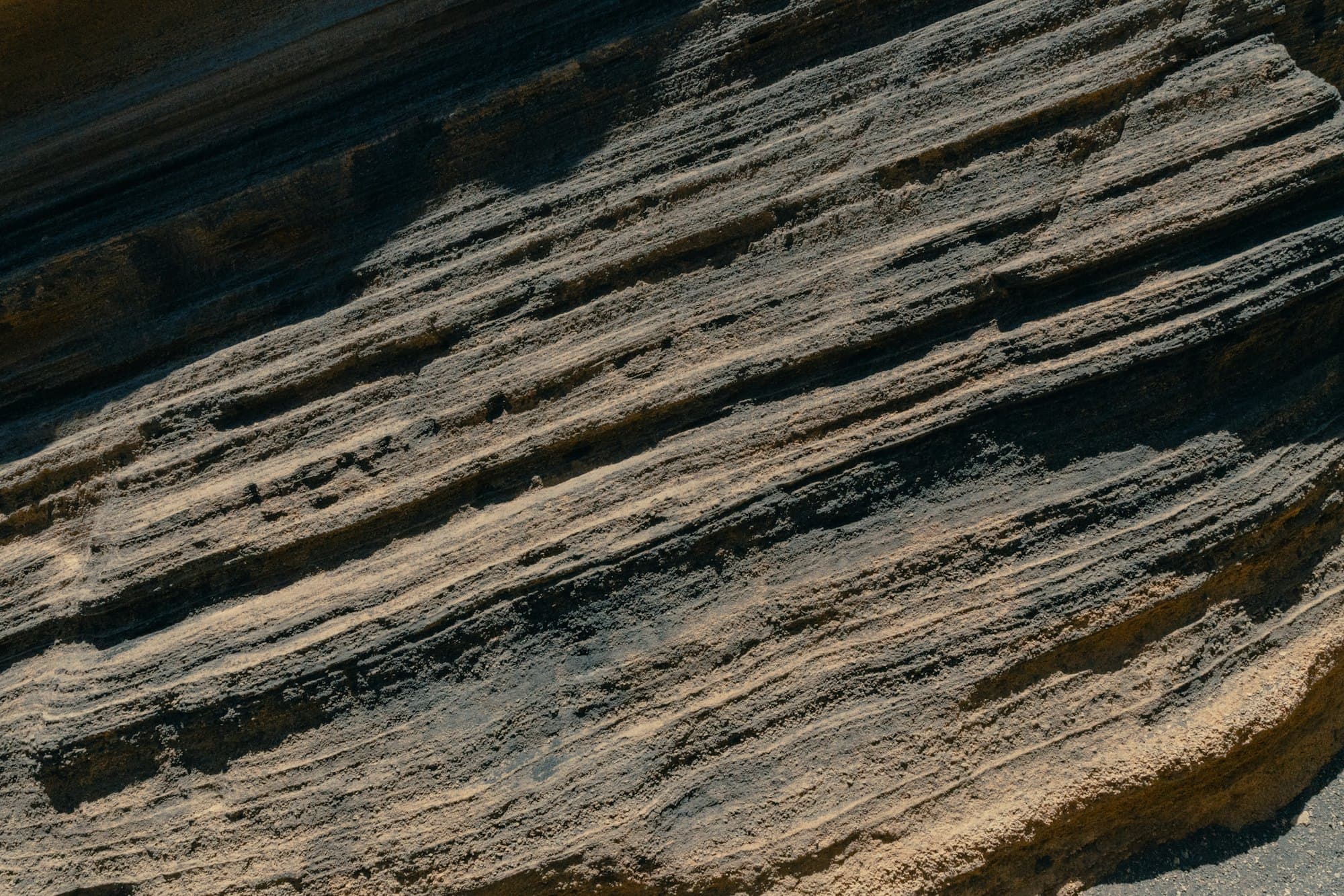 Tilted layers of volcanic rock, each band a different shade of grey and brown